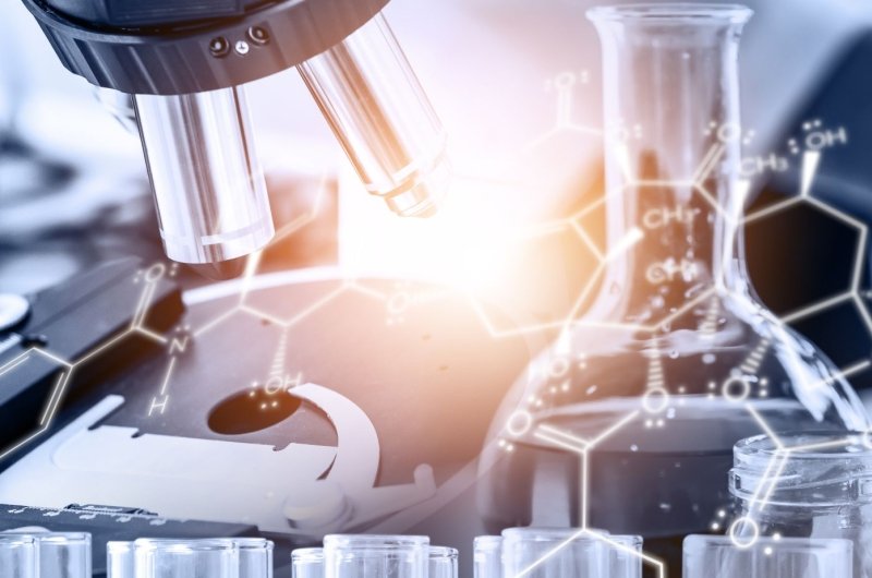 A microscope and a beaker over laid with a chemical makeup of a molecule